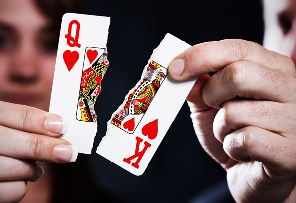Hands holding torn queen and king playing cards