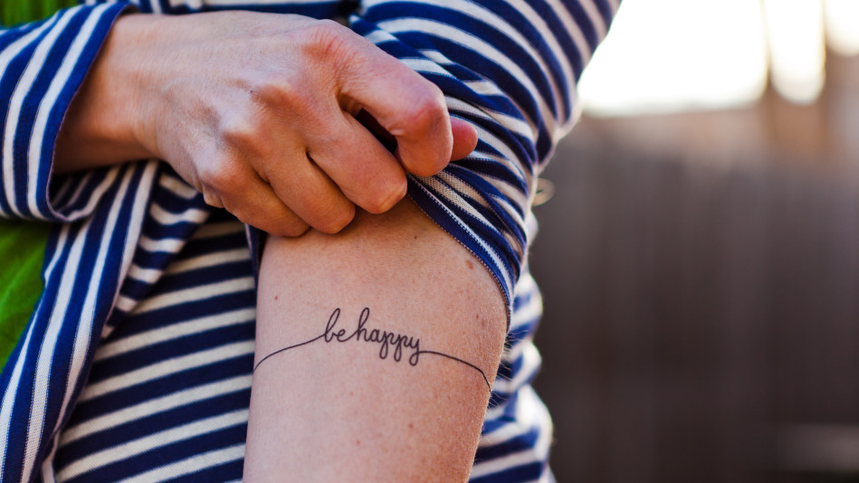 Woman exposes forearm tattoo that says "be happy"