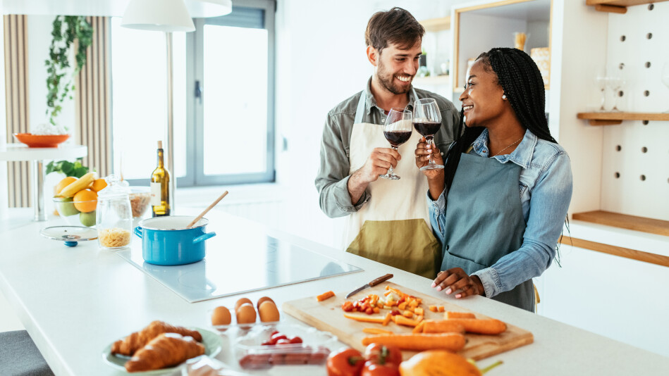 Interracial couple making dinner and drinking wine at home