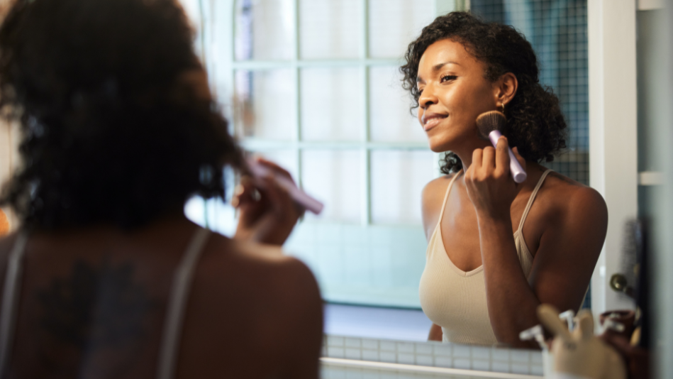 Woman applying makeup in bathroom mirror