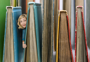 Woman peeking out from behind books