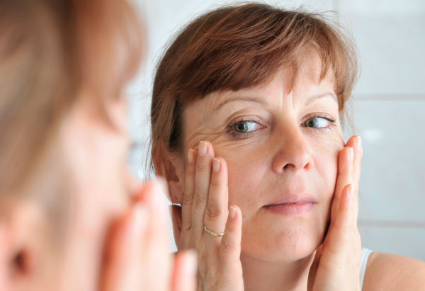 stressed woman examinging her face in mirror