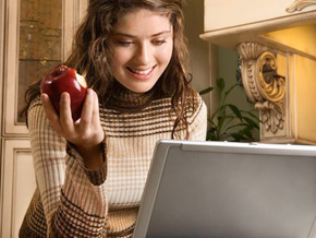 Woman eating an apple while on a computer