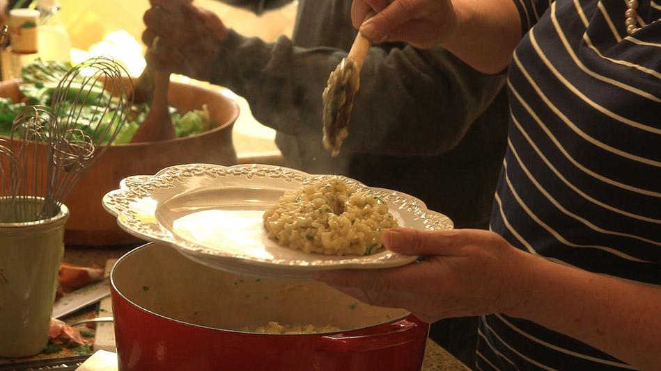 Lauren Tewes' risotto spooned onto plate, hands mixing salad